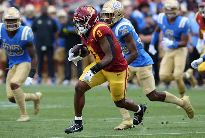 Nov 18, 2023; Los Angeles, California, USA; USC Trojans running back MarShawn Lloyd (0) runs against UCLA Bruins defensive back Alex Johnson (36) during the third quarter at United Airlines Field at Los Angeles Memorial Coliseum. Mandatory Credit: Jason Parkhurst-USA TODAY Sports