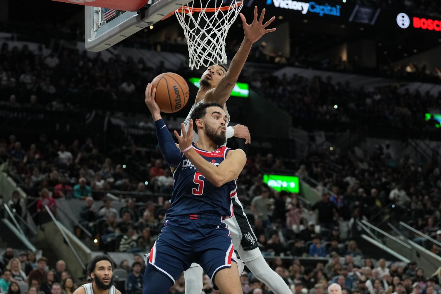 Washington Wizards guard Tyus Jones (5) looks to pass under the arm of San Antonio Spurs center Victor Wembanyama (1) in the second half at Frost Bank Center in San Antonio on Jan. 29, 2024.
