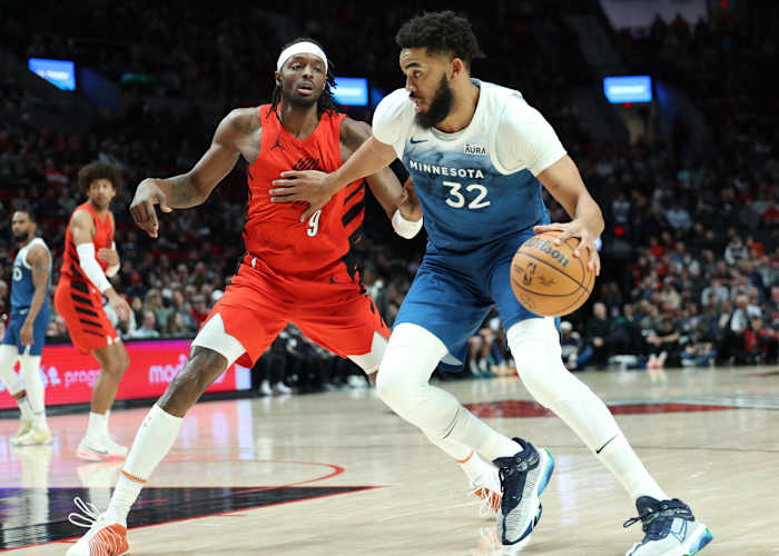 Feb 13, 2024; Portland, Oregon, USA; Minnesota Timberwolves center Karl-Anthony Towns (32) dribbles the ball past Portland Trail Blazers forward Jerami Grant (9) in the first quarter at Moda Center.