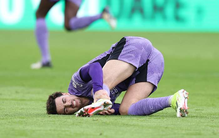Curtis Jones pictured holding his left ankle after suffering an injury during Liverpool's Premier League away game at Brentford in February 2024