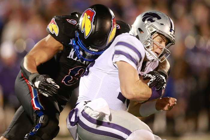 Kansas State senior quarterback Will Howard (18) is sacked by Kansas redshirt sophomore defensive lineman Austin Booker (9) during the fourth quarter of Saturday's Sunflower Showdown inside David Booth Kansas Memorial Stadium.