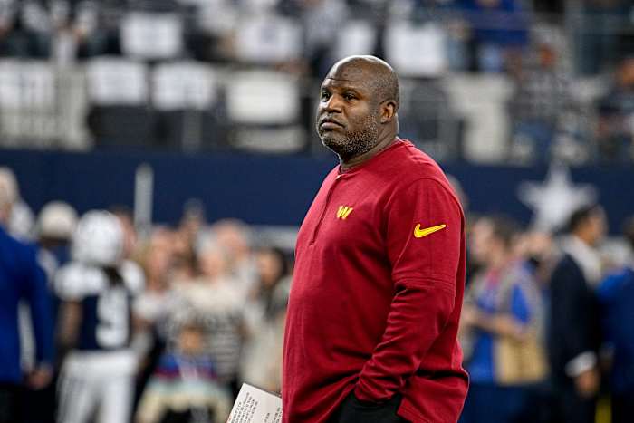 Eric Bieniemy stands on the sideline with his hands in his pockets