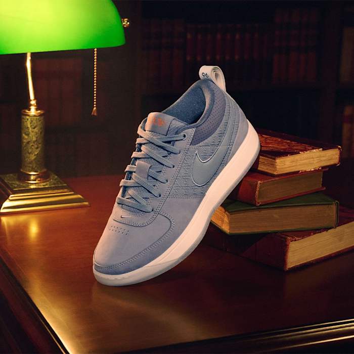 Devin Booker's grey Nike sneakers sit on top of books.