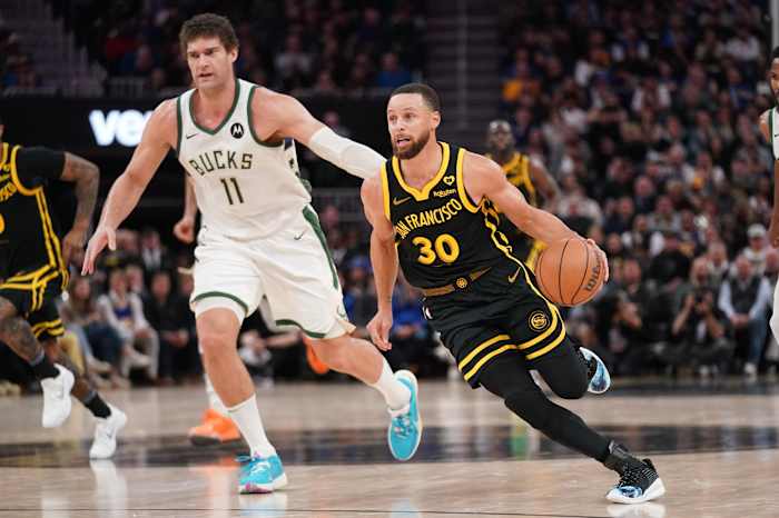Golden State Warriors guard Stephen Curry (30) dribbles past Milwaukee Bucks center Brook Lopez (11) i