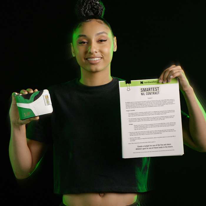 Juju Watkins holds up a contract and wallet in a photo shoot.