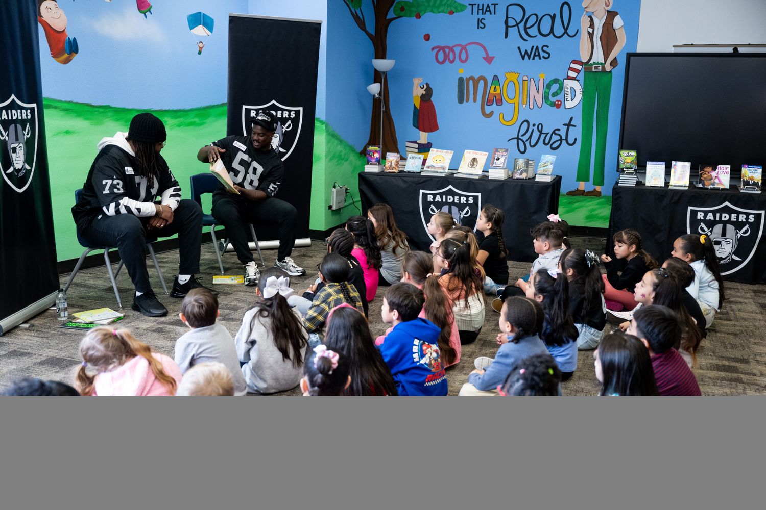 Las Vegas Raiders offensive tackle Jalen McKenzie (73) and linebacker Darien Butler (58) read to elementary school students as part of Nevada Reading Week.