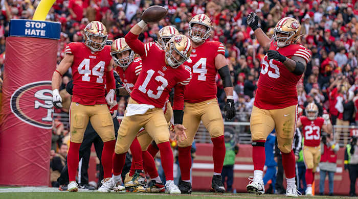 Brock Purdy spikes the ball after a touchdown with a group of teammates behind him