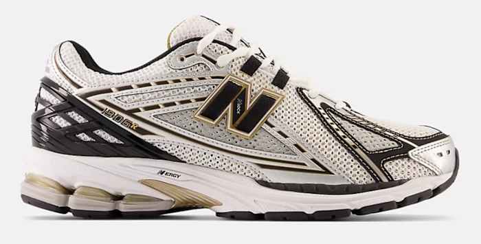 Side view of a white, black, and gold New Balance shoe.