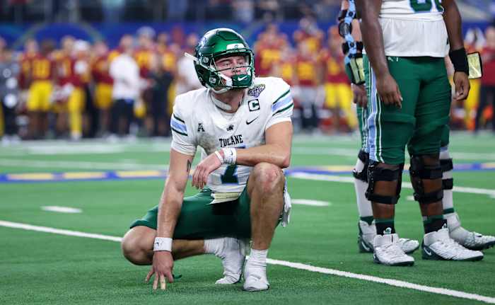 Michael Pratt kneels down on the field with one hand out to balance him, looking toward the sideline