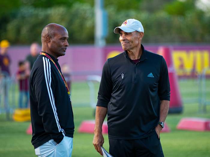 Ray Anderson (left) has his hands in his pockets as he talks to Herm Edwards (right)