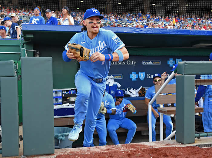 Bobby Witt Jr. runs out of the dugout holding a glove and with his mouth open in excitement