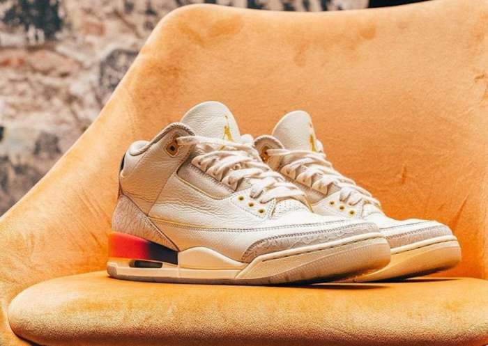White Air Jordan sneakers sit on an orange chair.