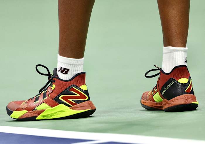 Side view of Coco Gauff's red, brown, and yellow New Balance tennis shoes.