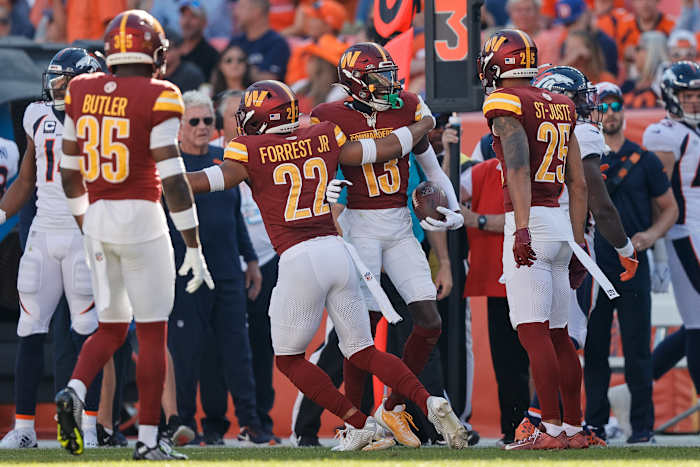 Washington Commanders cornerback Emmanuel Forbes Jr. (13) celebrates his interception with safety Darrick Forrest (22) and cornerback Benjamin St-Juste (25) and safety Percy Butler (35) in the third quarter against the Denver Broncos at Empower Field at Mile High.