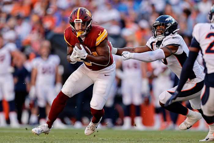 Washington Commanders running back Antonio Gibson (24) runs through the tackle of Denver Broncos linebacker Jonathon Cooper (0) in the fourth quarter at Empower Field at Mile High.