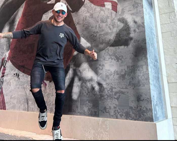 Johnny Manziel poses in front of his picture at a Texas A&M football game.