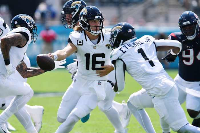 Trevor Lawrence passes off the ball to a running back as other Jaguars players run by him