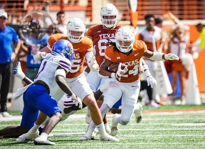 Texas Longhorns running back Jonathon Brooks (No. 24) breaks a tackle against Kansas Jayhawks defensive back Kenny Logan Jr. (No. 1).