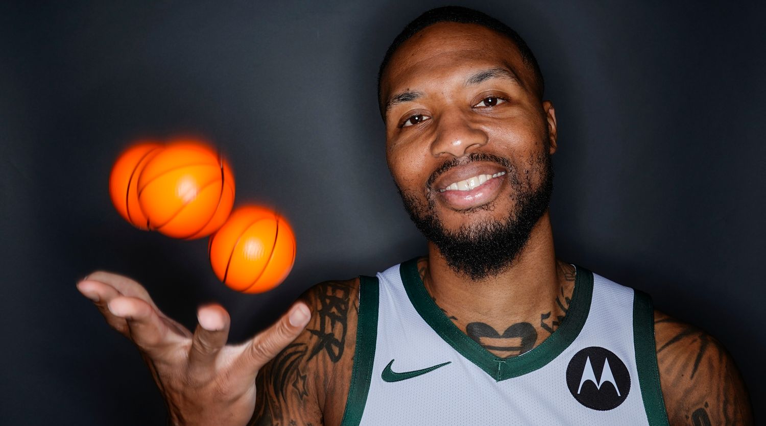 Damian Lillard throws up three mini basketballs while smiling for a picture at Bucks media day