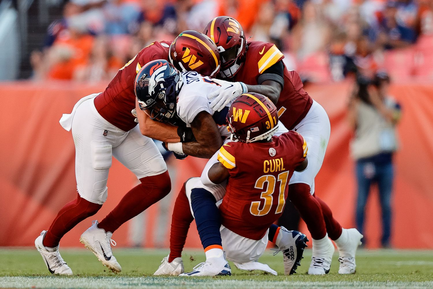 Denver Broncos wide receiver Courtland Sutton (14) is tackled by Washington Commanders safety Kamren Curl (31) and linebackers Cody Barton (57) and Jamin Davis (52) in the fourth quarter at Empower Field at Mile High.