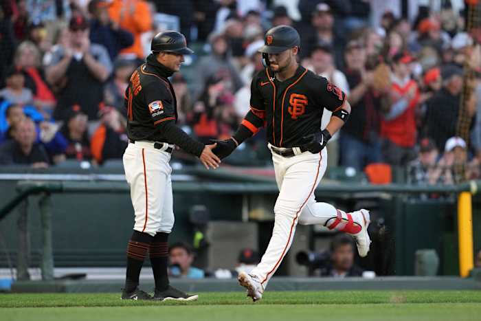 SF Giants designated hitter Michael Conforto (right) is congratulated by third base coach Mark Hallberg (left) after hitting a home run against the Texas Rangers during the fourth inning at Oracle Park. (2023)