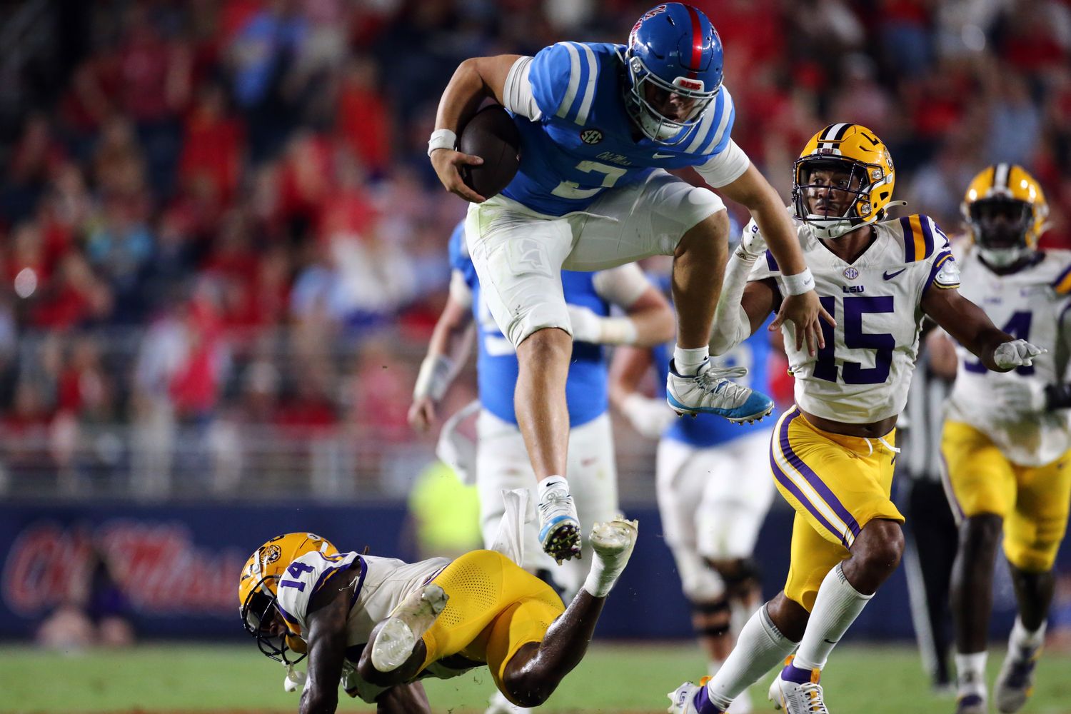 Sep 30, 2023; Oxford, Mississippi, USA; Mississippi Rebels quaterback Jaxson Dart (2) leaps over LSU Tigers defensive back Andre' Sam (14) during the second half at Vaught-Hemingway Stadium. Mandatory Credit: Petre Thomas-USA TODAY Sports