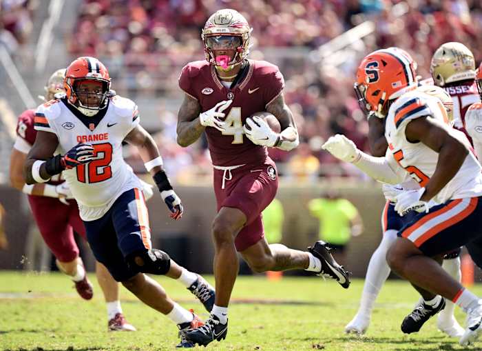 wide receiver Keon Coleman (4) runs with the ball as two Syracuse players run toward him