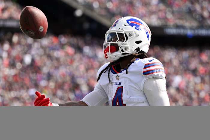 Buffalo Bills running back James Cook (4) tosses the ball after rushes against the New England Patriots during the first half at Gillette Stadium.