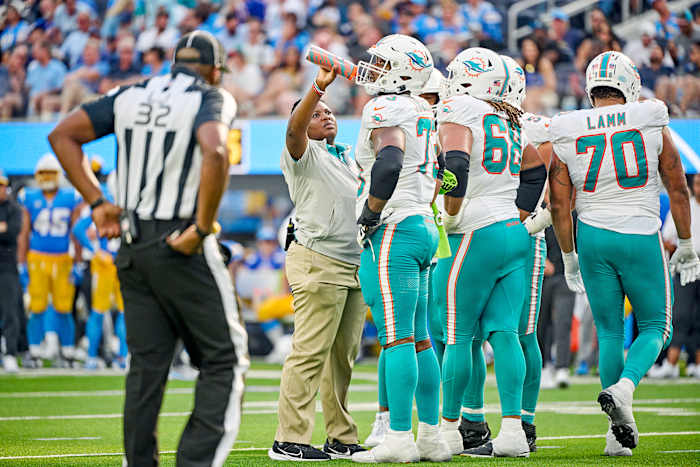 Dolphins assistant athletic trainer Jasmin Grimes runs onto the field with water during a game.