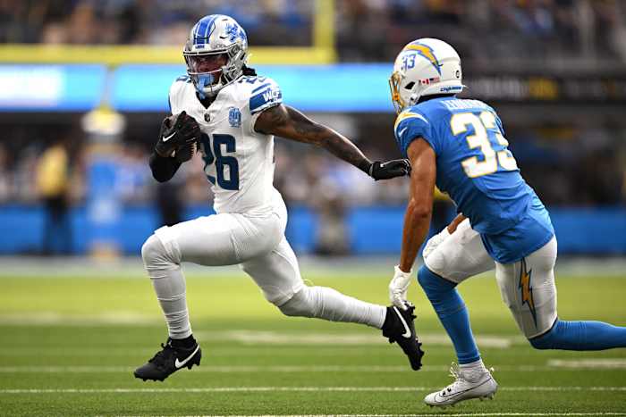 Detroit Lions running back Jahmyr Gibbs (26) runs the ball while defended by Los Angeles Chargers cornerback Deane Leonard (33) during the first half at SoFi Stadium.
