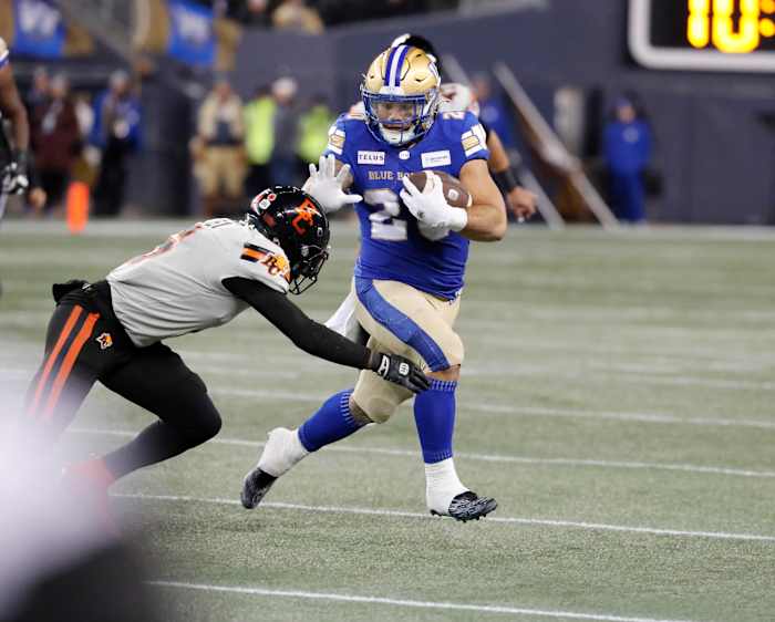 Nov 11, 2023; Winnipeg, Manitoba, CAN; Winnipeg Blue Bombers running back Brady Oliveira (20) breaks a tackle by BC Lions defensive back T.J. Lee (6) during the first half of the game at IG Field. Mandatory Credit: Bruce Fedyck-USA TODAY Sports