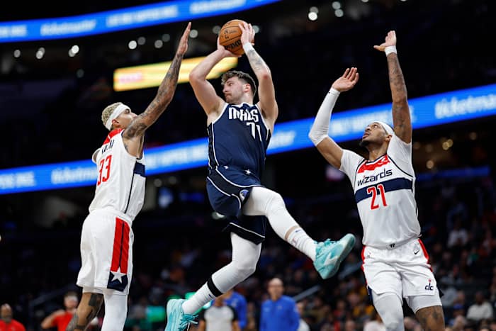 Dallas Mavericks star Luka Doncic throws a pass while being double-teamed by Washington Wizards' Kyle Kuzma and Daniel Gafford.