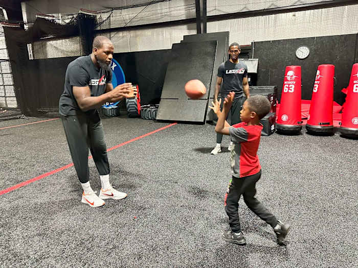 Mohamed Sanu plays catch at Legacy Sports Complex while Christian Blake watches in the background.