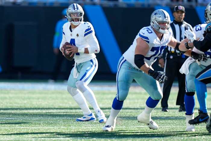 Dak Prescott steps back holding the ball, scanning the field