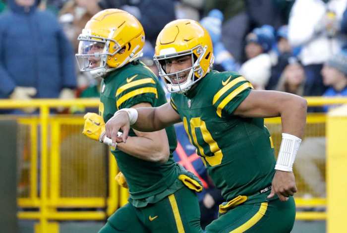 Jordan Love smiles as he runs off the field with wide receiver Christian Watson next to him