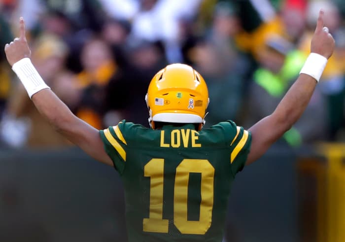 Jordan Love stands with his back to the camera with his arms up on either side