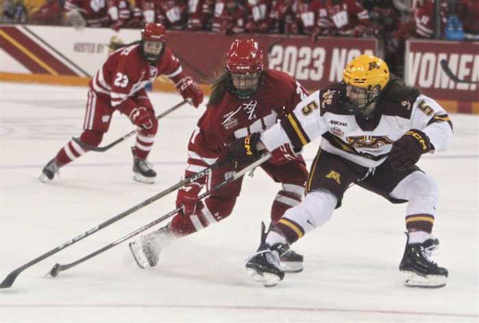 Wisconsin's Kirsten Simms (27) control the puck as Minnesota's Madeline Wethington defends during the teams' national semifinals at AMSOIL Arena in Duluth, Minn. on Friday March 17, 2023. Uw Minnesota Frozen Four 4 March 17 2023