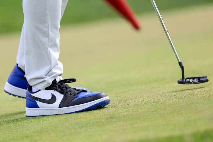 Side view of white, black, and blue Air Jordan golf shoes.
