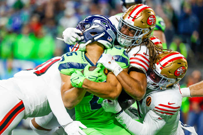San Francisco 49ers linebacker Fred Warner (54) and linebacker Randy Gregory (5) tackle Seattle Seahawks running back Zach Charbonnet (26) on a rushing attempt.