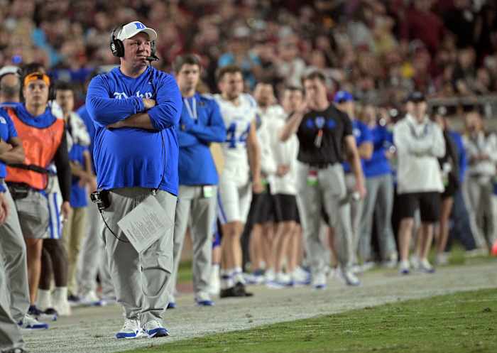Mike Elkos walks along the Duke sideline with his arms crossed