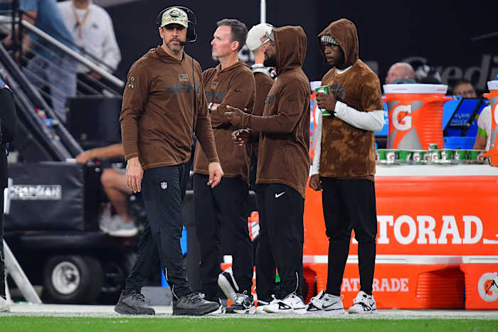Aaron Rodgers walks along the sideline past a bunch of Jets staff