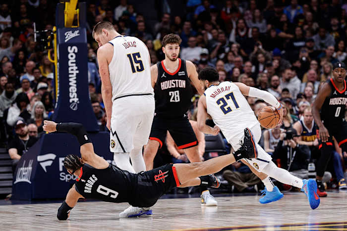 Rockets forward Dillon Brooks falls to the court after colliding with Nuggets center Nikola Jokic as he screens for guard Jamal Murray.