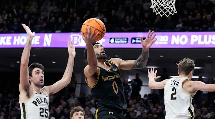 Northwestern point guard Boo Buie drives to the basket for a layup between two Purdue defenders.