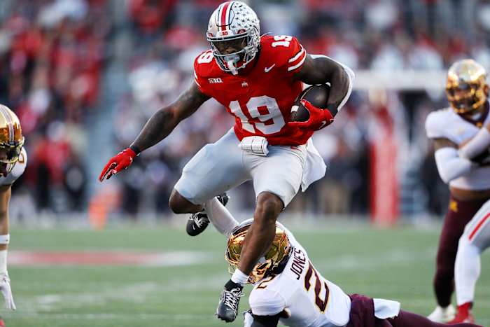 Ohio State Buckeyes running back Chip Trayanum (19) hurdles Minnesota Golden Gophers defensive back Tre'Von Jones (2) during the first quarter at Ohio Stadium.