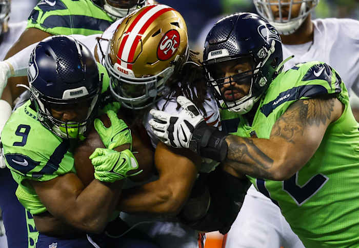 San Francisco 49ers linebacker Fred Warner (54) tackles Seattle Seahawks running back Kenneth Walker III (9) as offensive tackle Abraham Lucas (72) blocks during the second quarter at Lumen Field.