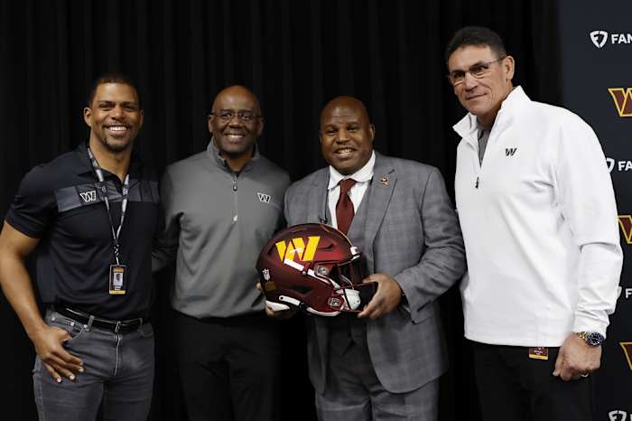 Eric Bieniemy (holding helmet) poses with (L-R) Washington Commanders team president Jason Wright, general manager Martin Mayhew, and head coach Ron Rivera.