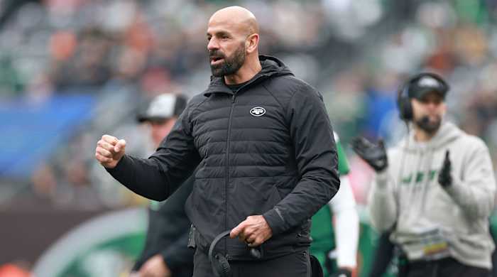 Robert Saleh pumps his fist while holding his headset in the other hand