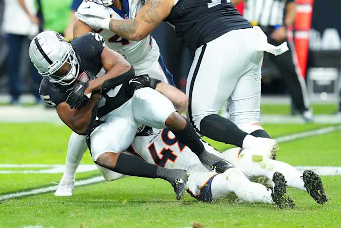 Las Vegas Raiders running back Zamir White (35) is tackled by Denver Broncos linebacker Alex Singleton (49) during the second quarter at Allegiant Stadium.