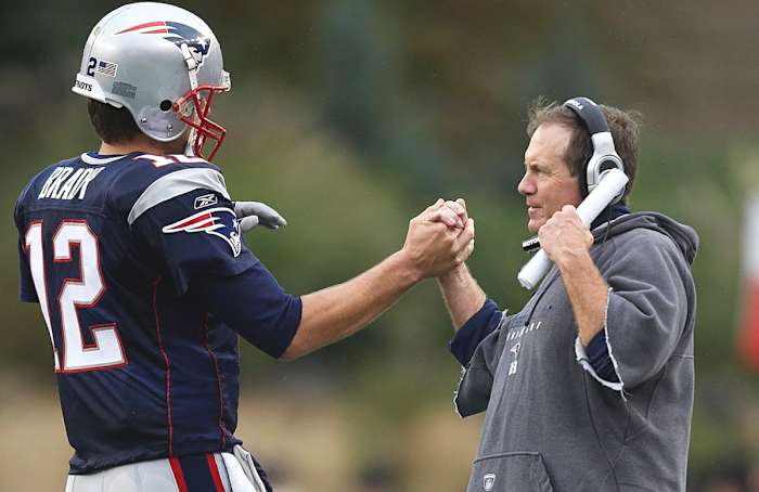 Bill Belichick clasps hands with Tom Brady.