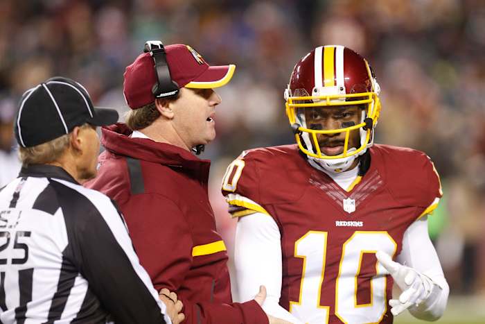 Washington Redskins head coach Jay Gruden (C) talks to Redskins quarterback Robert Griffin III (10) in the second half against the Philadelphia Eagles at FedEx Field. The Redskins won 27-24. Mandatory Credit: Geoff Burke-USA TODAY Sports